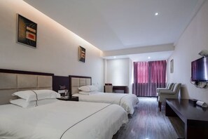 Quarto de hotel com duas camas, televisão, escrivaninha e uma cadeira.