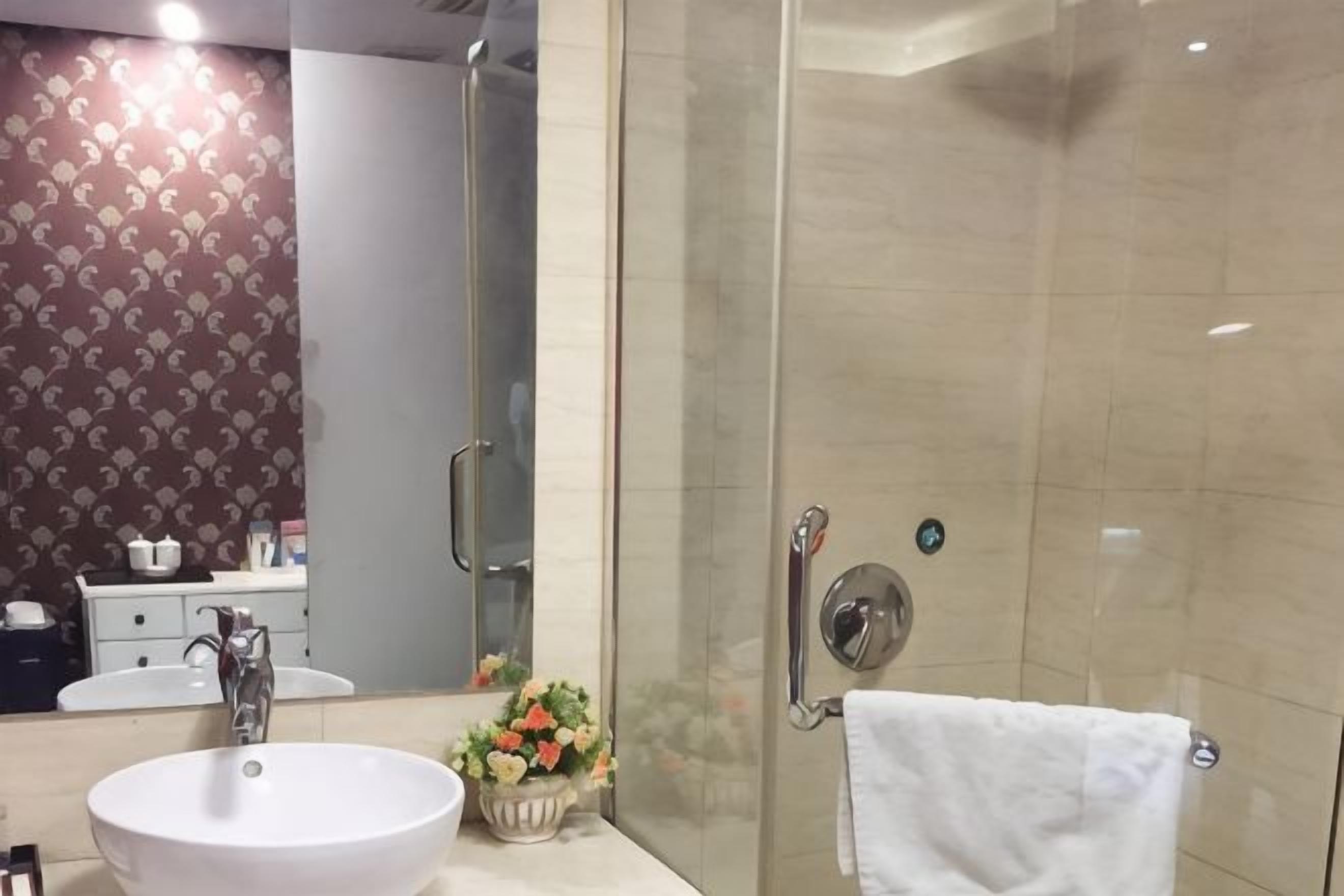 Un bany amb una cabina de dutxa de vidre, un lavabo i un mirall.