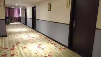 Un couloir d'hôtel avec un revêtement de sol en moquette, des portes et un comptoir d'accueil situé au fond.