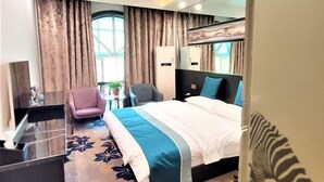 A modern hotel room with a large bed, a desk, a chair, and a mirror. - Borui Business Hotel (Tongxiang)