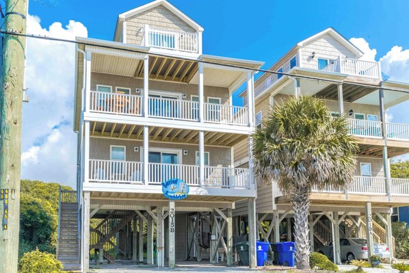 A multi-story beachfront building with balconies, a covered entrance, and a sign indicating a bumblebee theme.