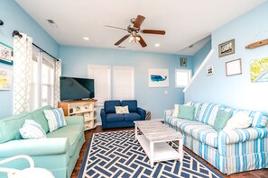 A living room with a ceiling fan, two sofas, a coffee table, and a TV.