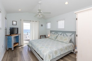 Una camera da letto con un letto, una TV, una ventola a soffitto e vista sul mare.
