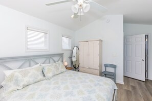 A bedroom with a bed, a wardrobe, a mirror, and a door.