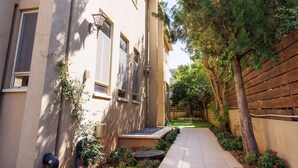 A narrow pathway leading to a building with a small garden area, a wooden fence, and a tree. - HaSharon Tranquil Villa by Sea N' Rent (Hod HaSharon)