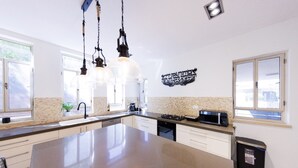 A modern kitchen with a large island, pendant lights, and a microwave. - HaSharon Tranquil Villa by Sea N' Rent (Hod HaSharon)