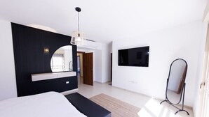 A modern bedroom with a bed, a bedside table, a mirror, a TV, and a standing lamp. - HaSharon Tranquil Villa by Sea N' Rent (Hod HaSharon)