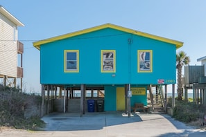 Un bâtiment à deux étages, à la façade bleue et jaune, doté d’une entrée couverte et d’une enseigne indiquant qu’il s’agit d’un centre de soins pour les personnes en vacances.