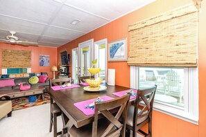 A dining area with a wooden table, chairs, and a view of the outdoors through a window.