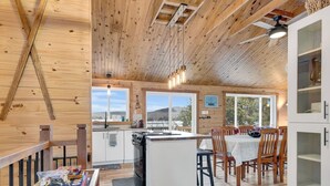 A wooden interior with a kitchen, dining area, and large windows.