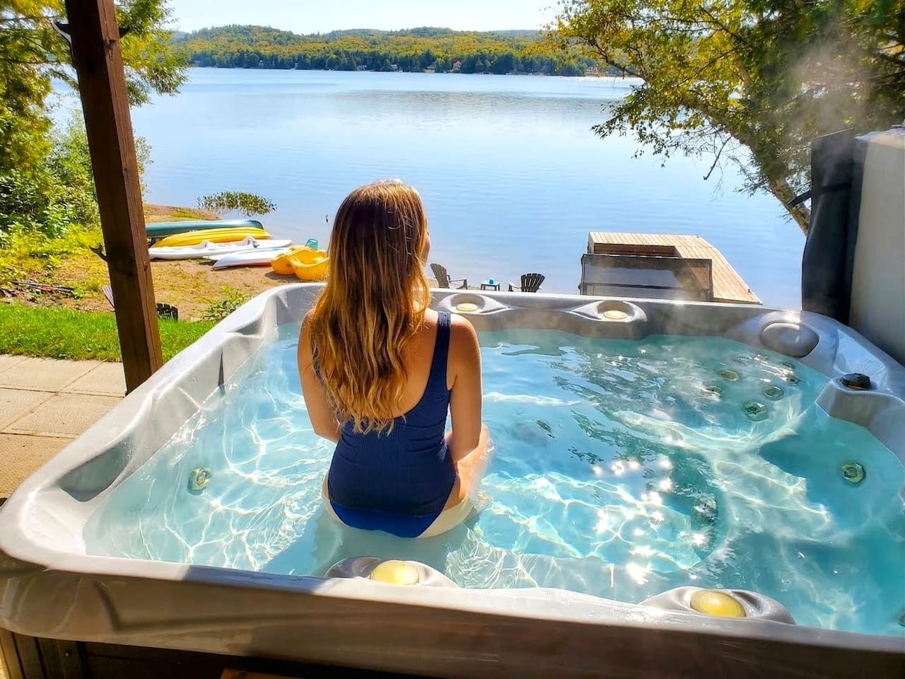 Una persona relajándose en un jacuzzi con vista al lago.