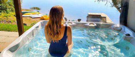 Una persona relajándose en un jacuzzi con vista al lago.