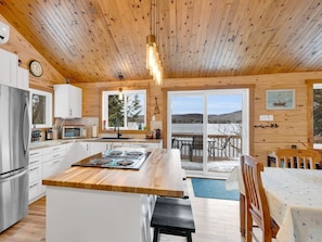 A cabin interior with a kitchen, dining area, and a view of the outdoors.