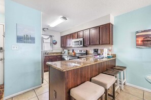 A kitchen with a central island, dark wood cabinets, a microwave, and a sink. - Seaside Beach 2102- Beachside! Ground floor (Orange Beach)