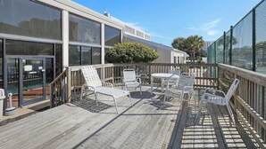 A deck with outdoor seating, a pool, and a building with large windows. - Seaside Beach 2102- Beachside! Ground floor (Orange Beach)