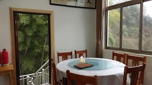 Ein Essbereich mit einem runden Tisch, Stühlen und einem Fenster mit Blick auf Bäume.