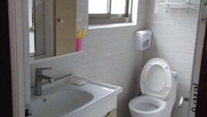 Ein Badezimmer mit einem weißen Waschbecken, einer Toilette und einem Fenster über dem Waschbecken.