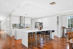 Una cocina moderna con armarios blancos, electrodomésticos de acero inoxidable y una isla central con taburetes de bar.