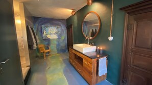 Un baño con tocador de madera, un espejo grande y un cuadro en la pared.