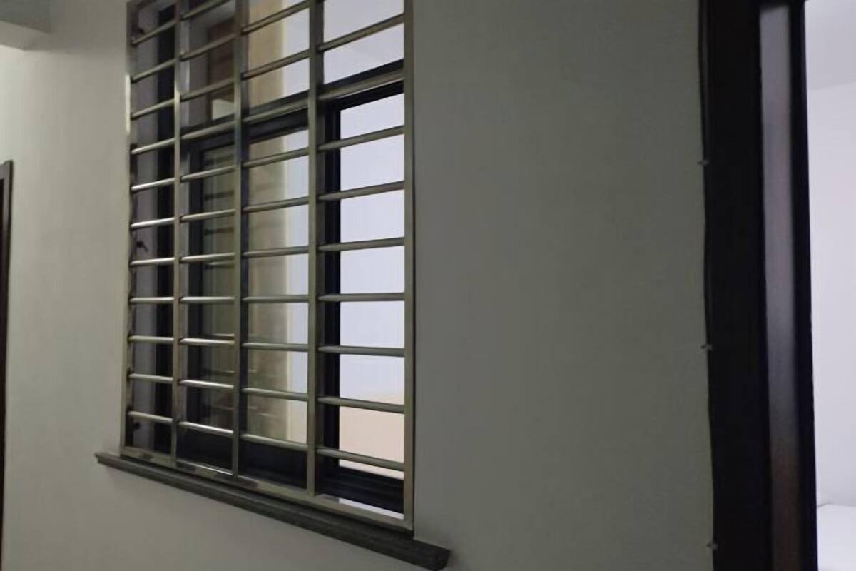 A window with a metal grid design, a dark frame, and a white wall.