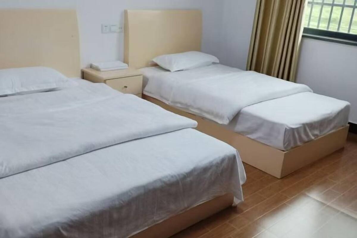 A hotel room with two beds, a nightstand, and a window with curtains.