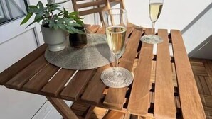 Une table en bois, un pot de fleurs, un verre de vin blanc et une chaise.