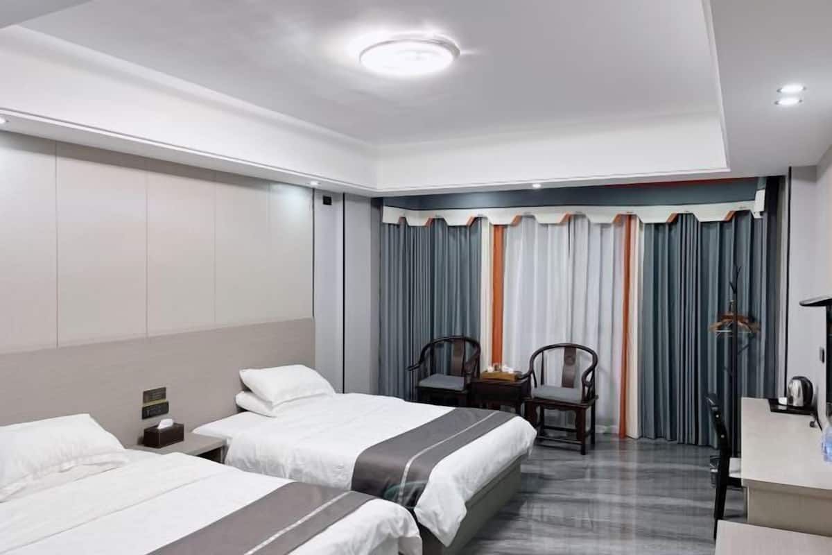 A hotel room with two beds, a desk, and a chair.