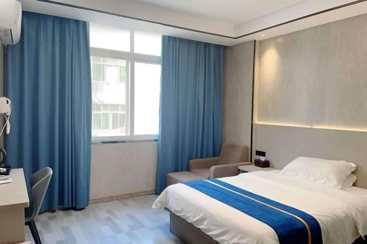 A hotel room with a bed, a desk, and a chair.