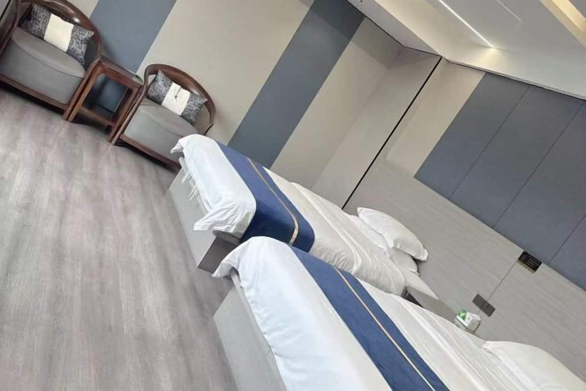 A modern hotel room with two beds, a wooden chair, and a small table.