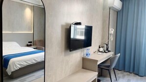 A hotel room with a bed, a desk, a TV, and a mirror. - Fuding New Era Business Hotel (Fuding)