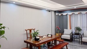 A dining area with a wooden table, chairs, and a bench. There are potted plants and a vase with flowers. - Fuding New Era Business Hotel (Fuding)