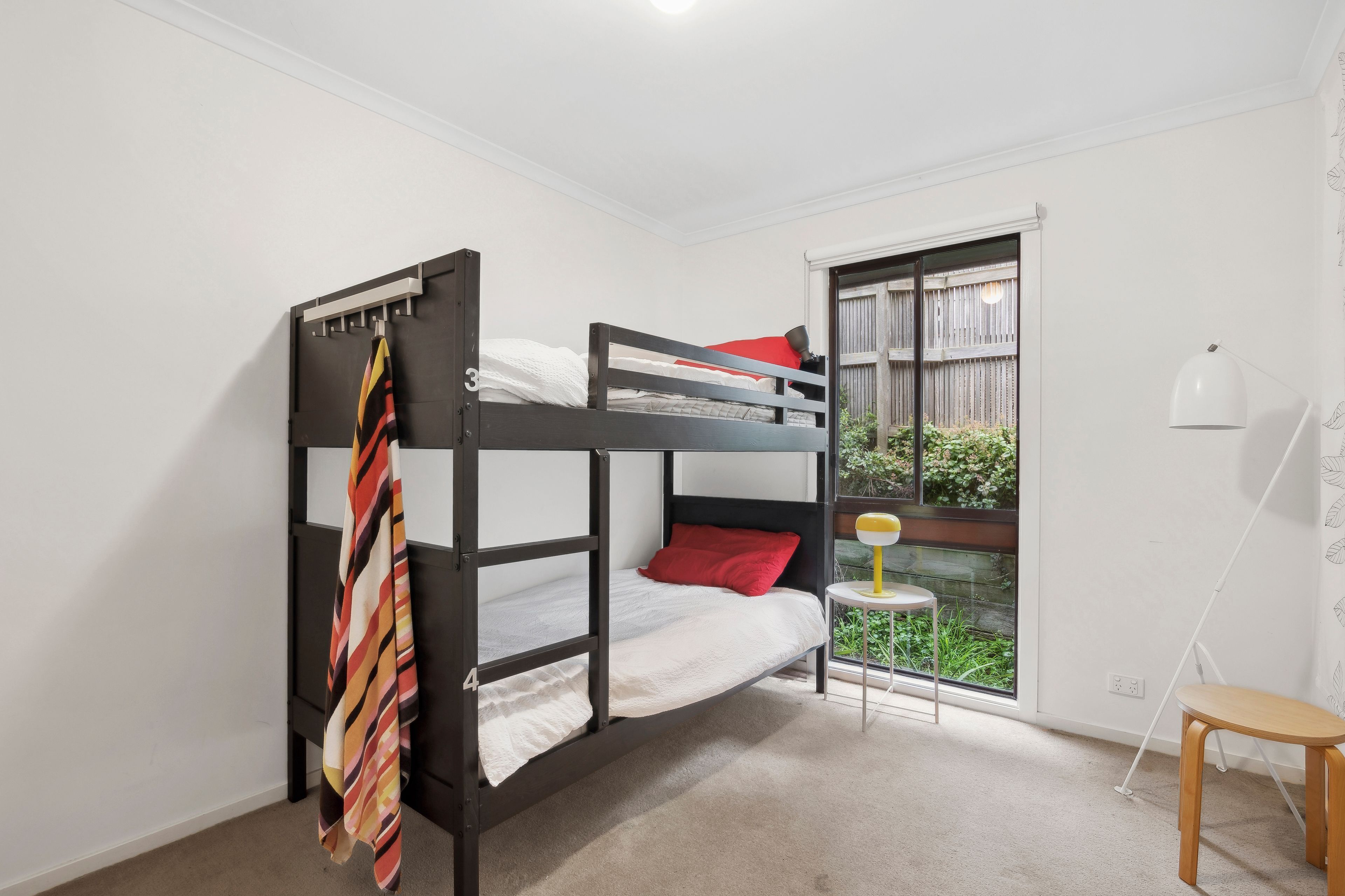 Une chambre avec un lit superposé, une fenêtre, une petite table et une lampe.