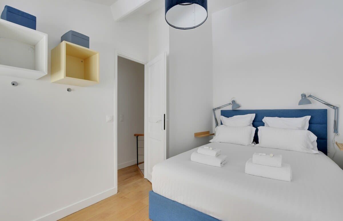 Un dormitorio con cama, mesitas de noche, lámpara colgante y muebles empotrados.