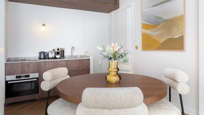 Une cuisine moderne avec des meubles en bois, un four encastré et un coin repas comprenant une table ronde et quatre chaises rembourrées.