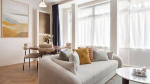 Un salon moderne comprenant un canapé, une table basse et un coin repas avec des chaises.