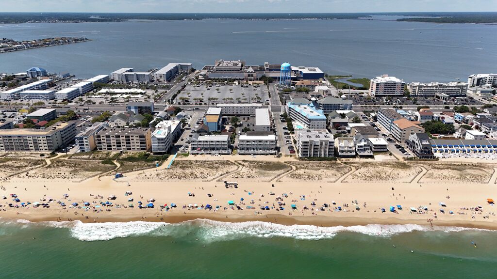Vue aérienne d’une ville côtière avec une plage, des bâtiments et une étendue d’eau.