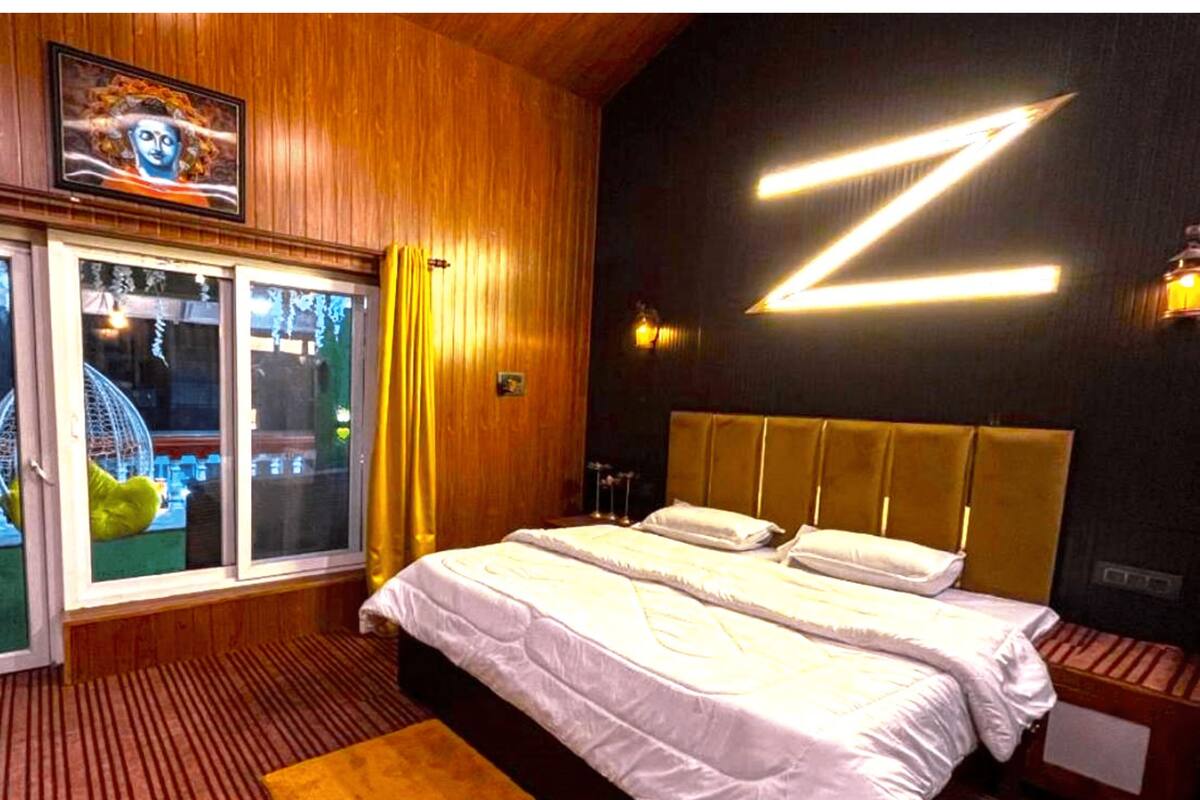 A modern bedroom with a large bed, wooden paneling, a large window with curtains, and a unique wall design.