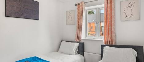 Un dormitorio con dos camas, una ventana con cortinas y obras de arte en las paredes.