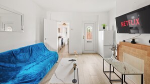 A modern living room with a blue sofa, a marble coffee table, and a TV displaying 'NETFLIX'. - Reading Retreat Spacious 5 Bedroom House (Reading)