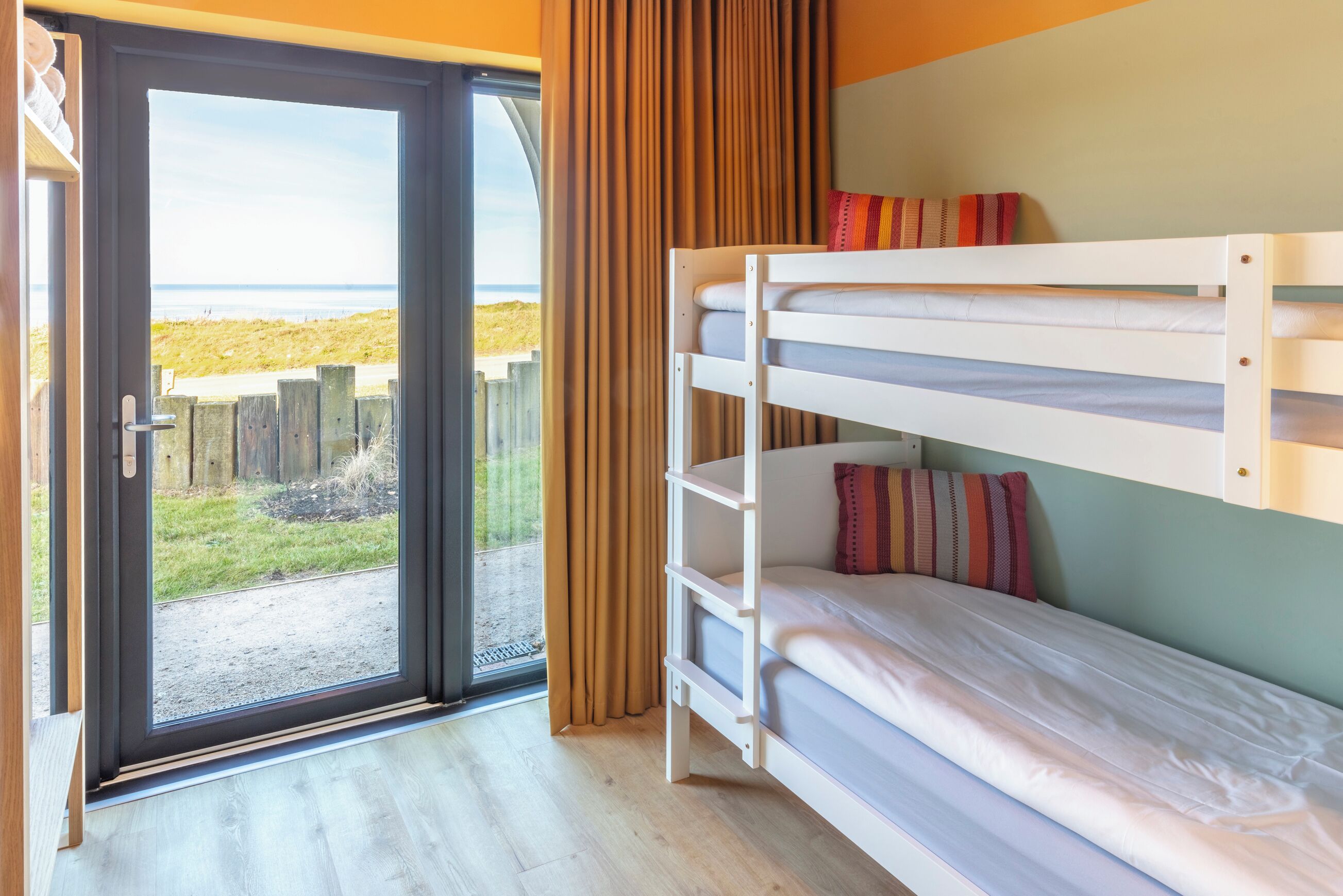 Habitación con literas y vista al mar a través de una puerta de vidrio.
