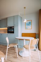 A modern kitchen with light blue cabinets, a round table with chairs, and a pendant light.
