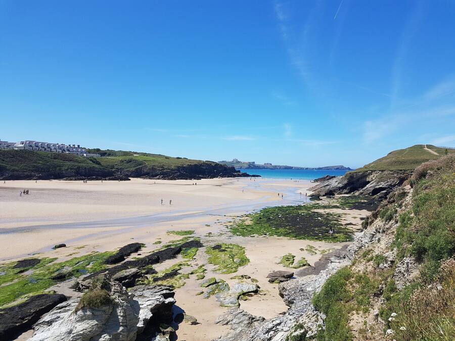Ein Küstenstrand mit felsigem Gelände und blauem Himmel.