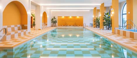 Una piscina con baldosas de cuadros, rodeada de muros con aberturas en arco y plantas en macetas.