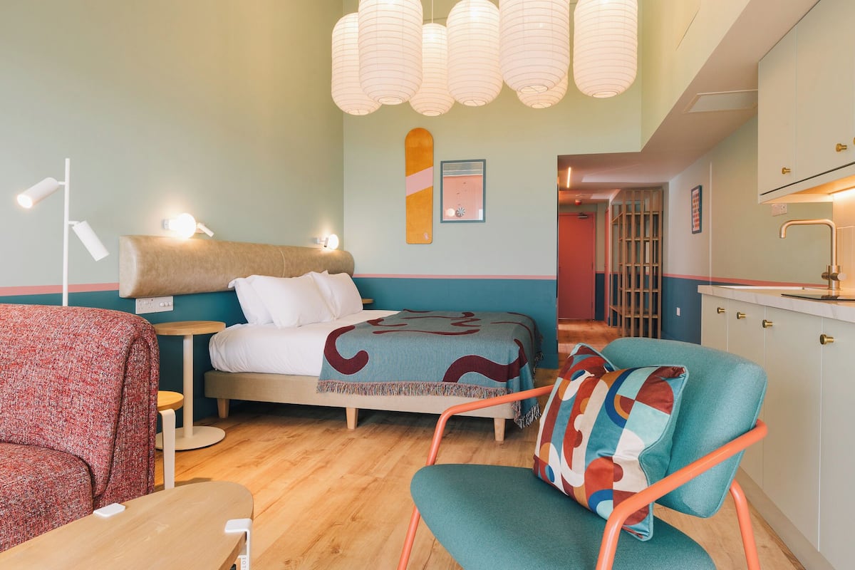 Une pièce confortable avec un lit, une chaise, une petite table et un coin cuisine.