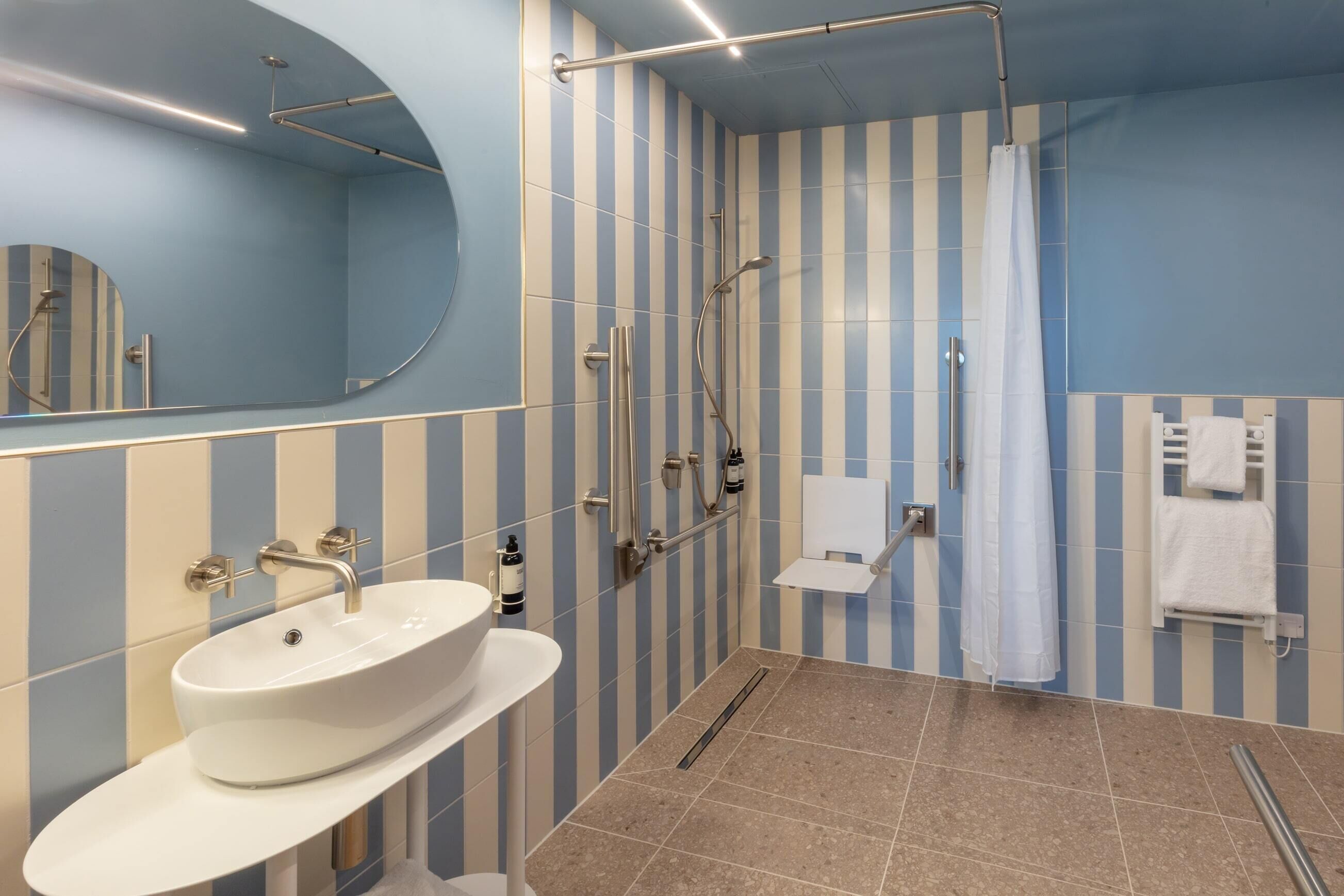 Une salle de bain moderne avec un grand lavabo ovale, une douche dotée d’une porte en verre et un miroir au-dessus du lavabo.