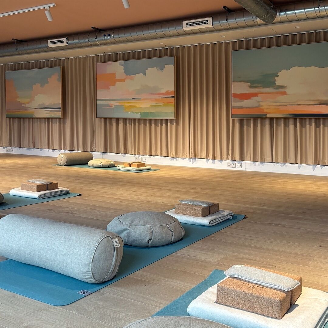 A yoga studio with wooden floors, yoga mats, and blocks.
