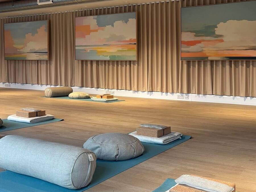 A yoga studio with wooden floors, yoga mats, and blocks.
