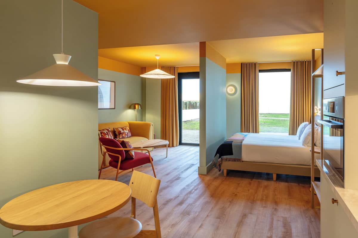 Une chambre d’hôtel équipée d’un lit, d’un bureau, d’une chaise, d’une table et offrant une vue sur l’extérieur.