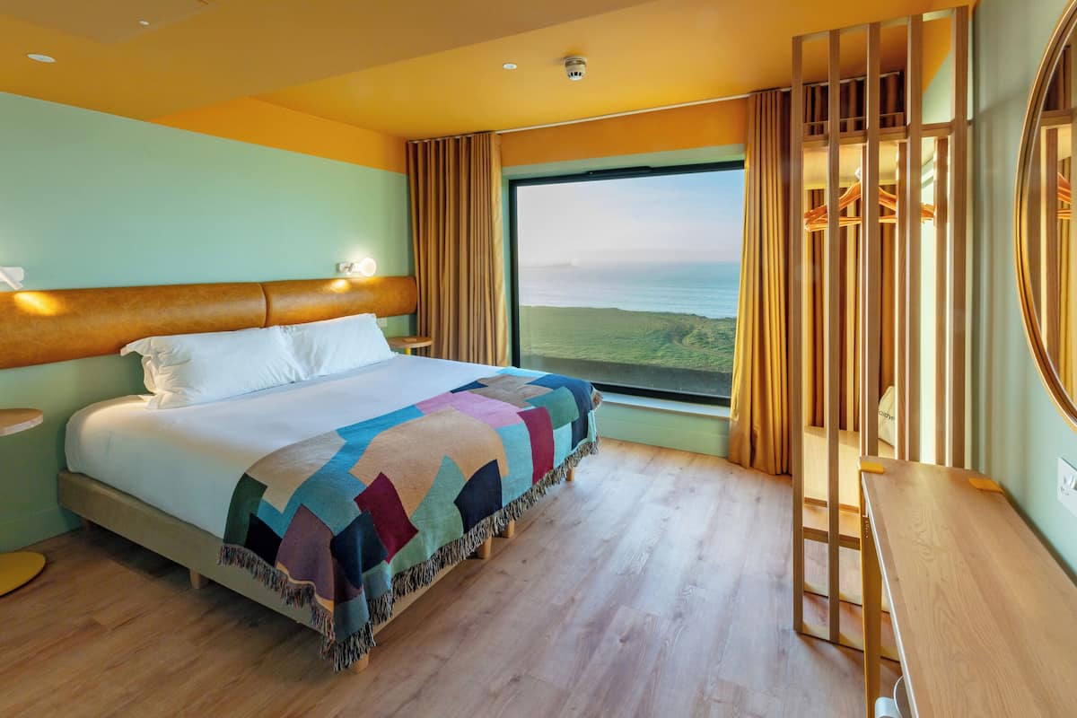 Une chambre d’hôtel avec un grand lit, une vue sur la mer et un bureau en bois.