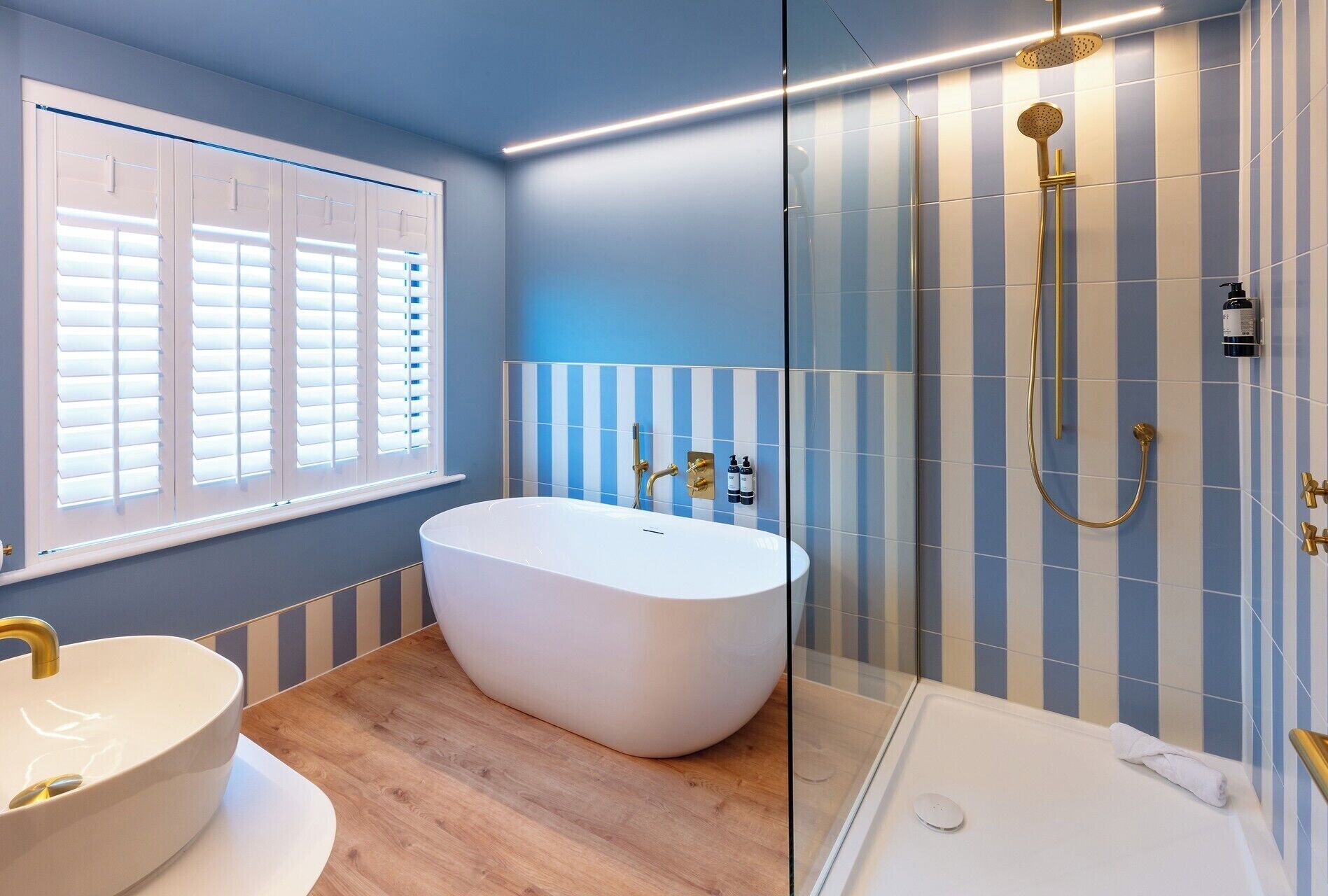 A modern bathroom with a freestanding bathtub, a sink with a gold faucet, and a shower with a gold showerhead.